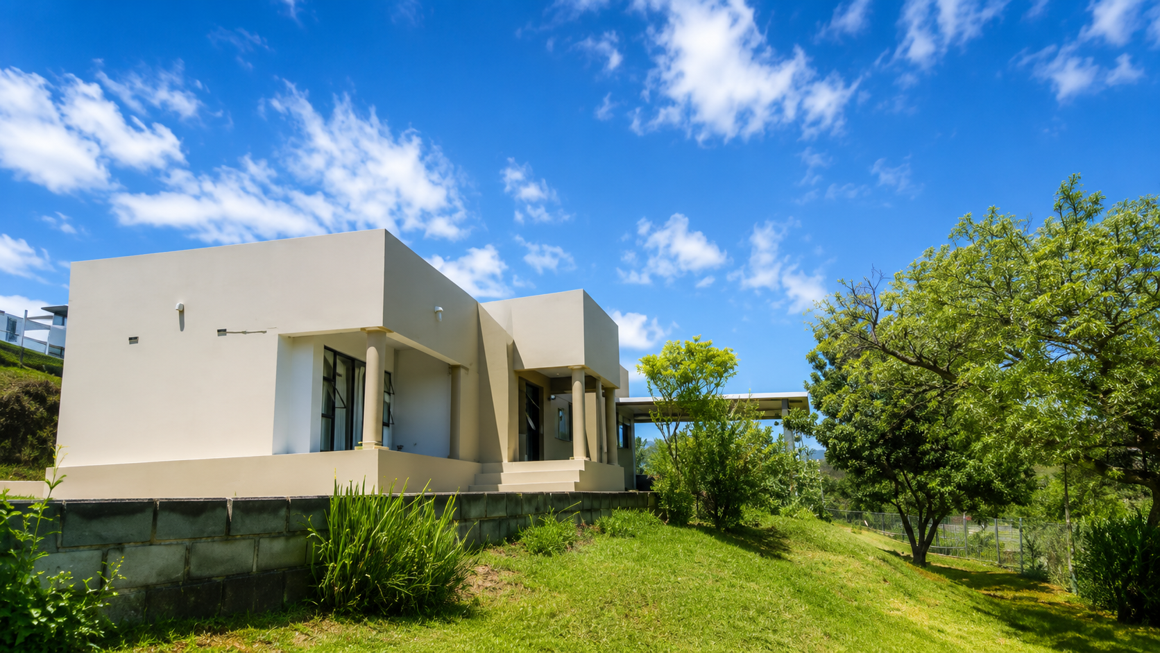 A Hidden Gem Guesthouse set on a green hillside in Inanda under a bright blue sky